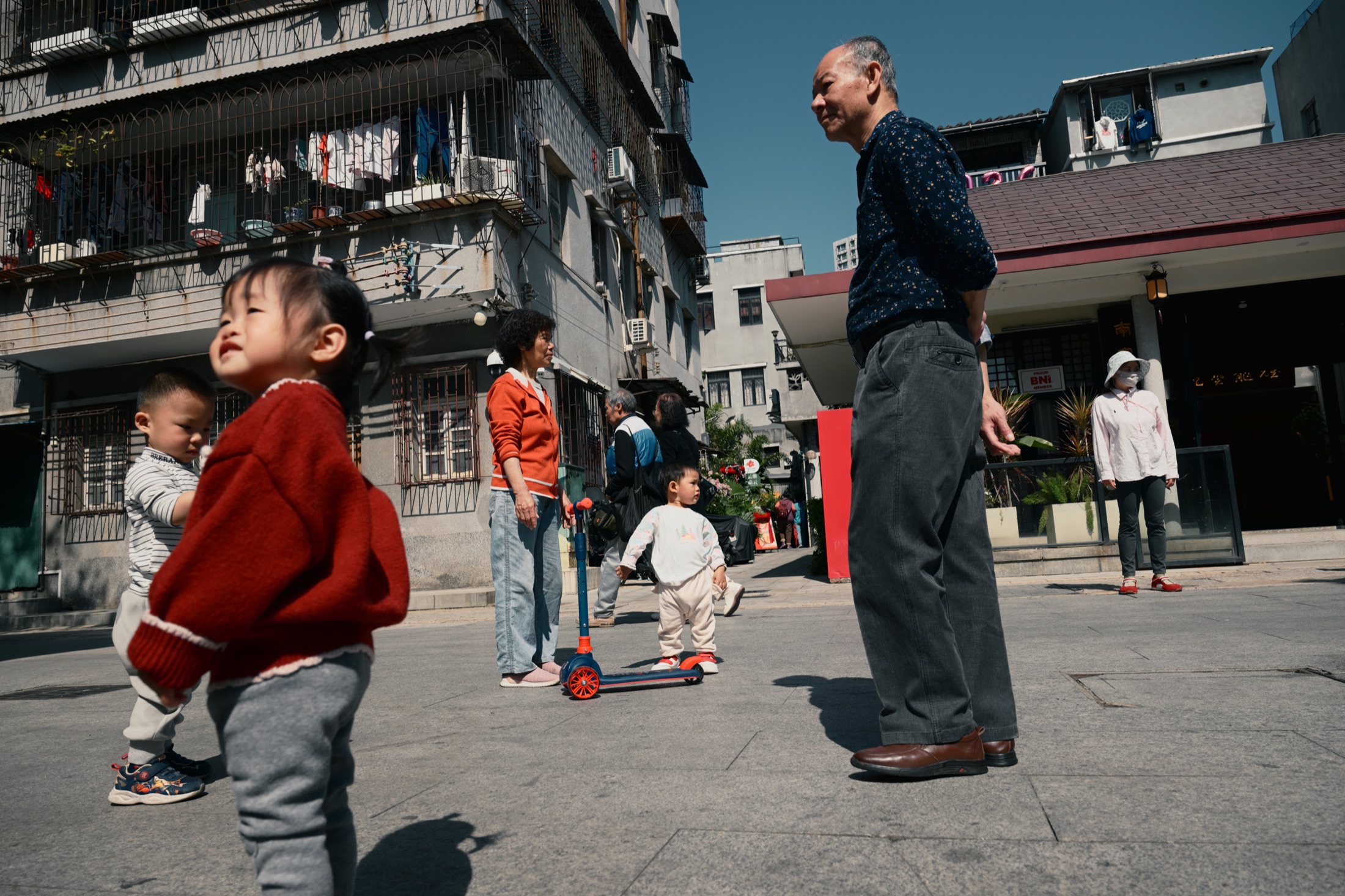 阳光下的街角，孩子与老人分别望向不同方向